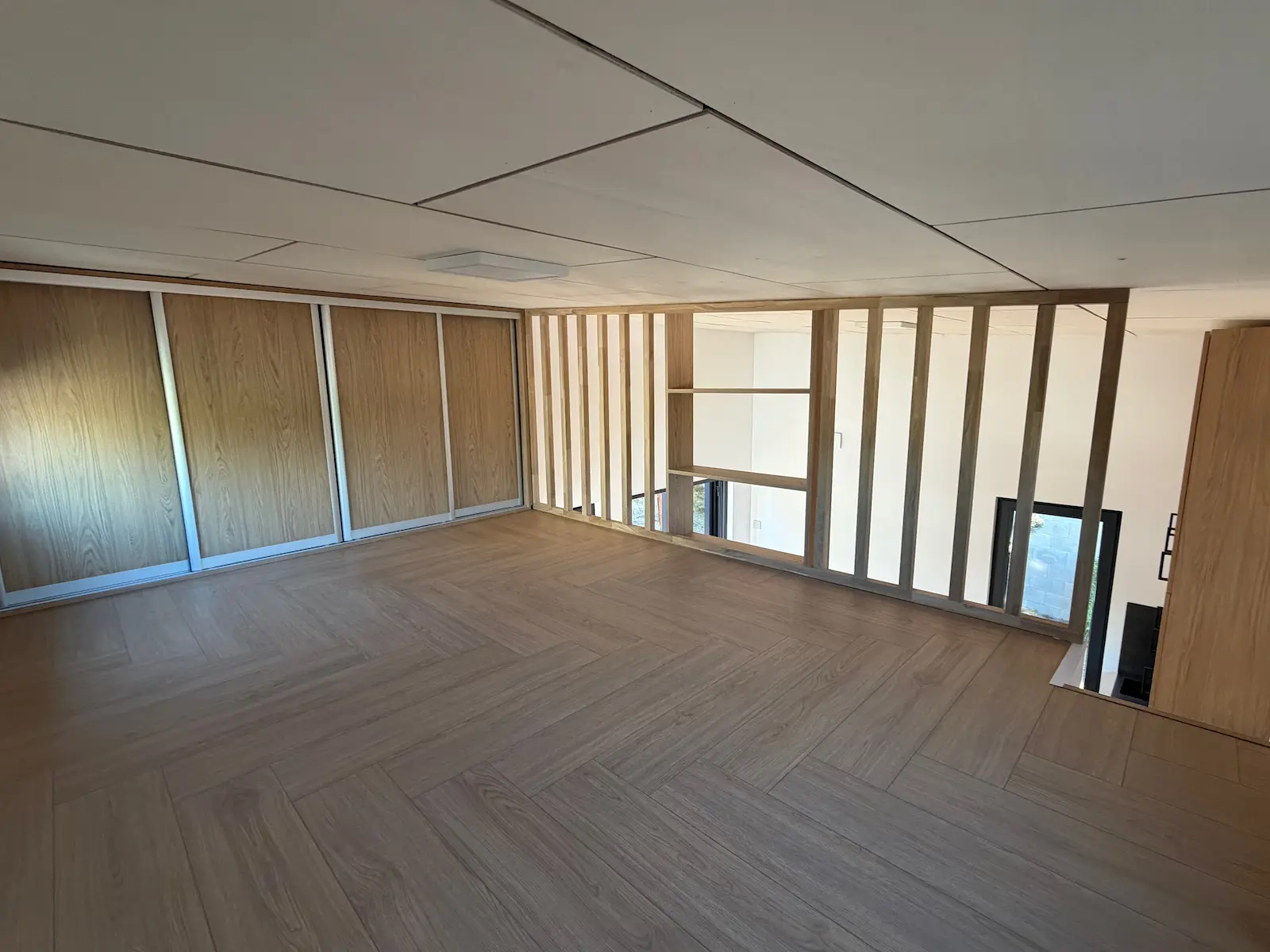 Spací loft s dřevěnou dělicí stěnou a vestavěnými skříněmi