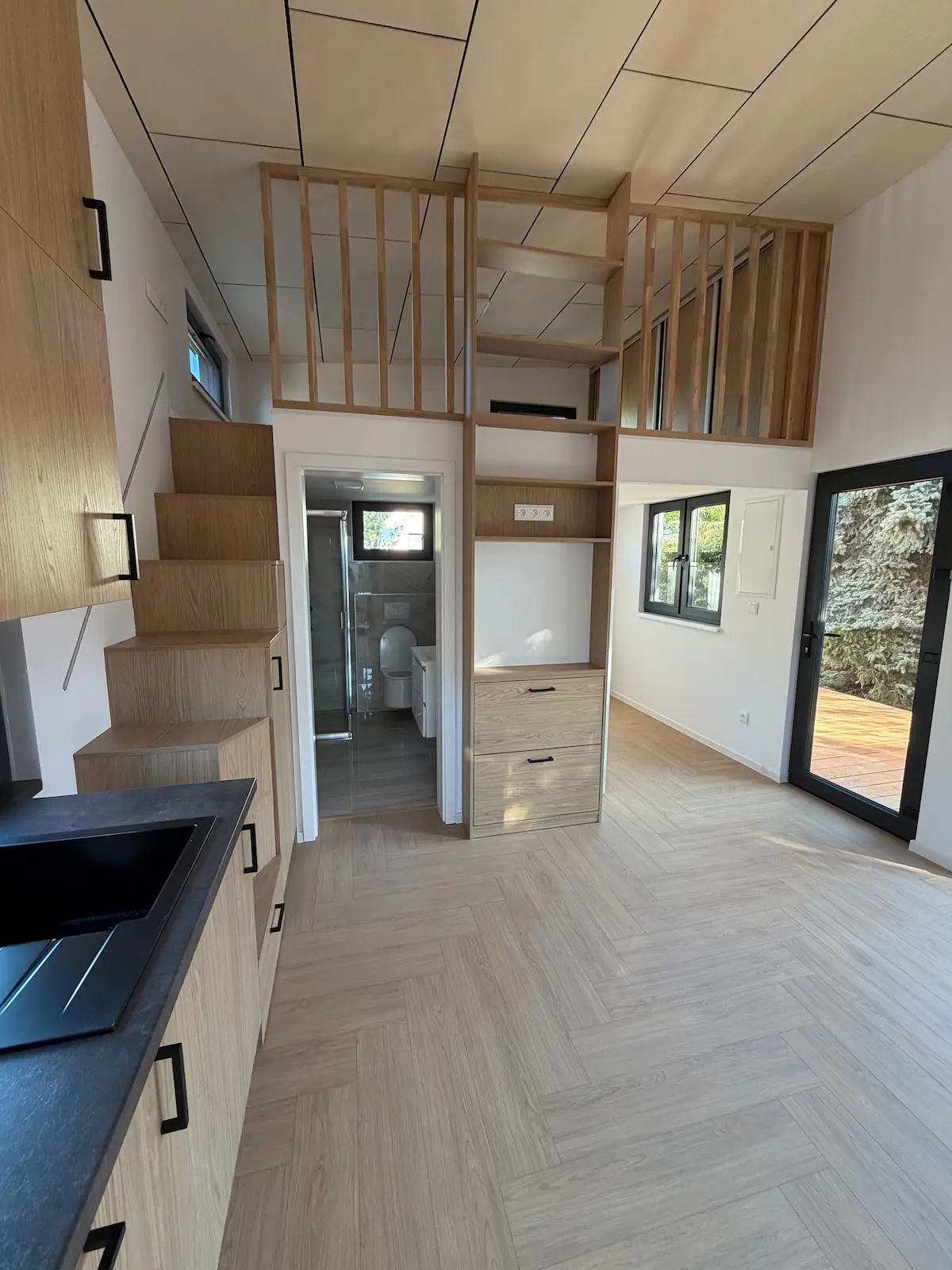 Interiér domu s pohledem na spací loft, koupelnu a vestavěné úložné prostory